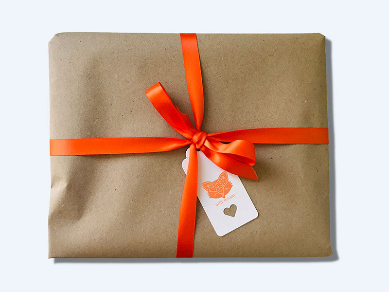 Gift wrapping; brown paper tied up with an orange satin ribbon and a gift tag.